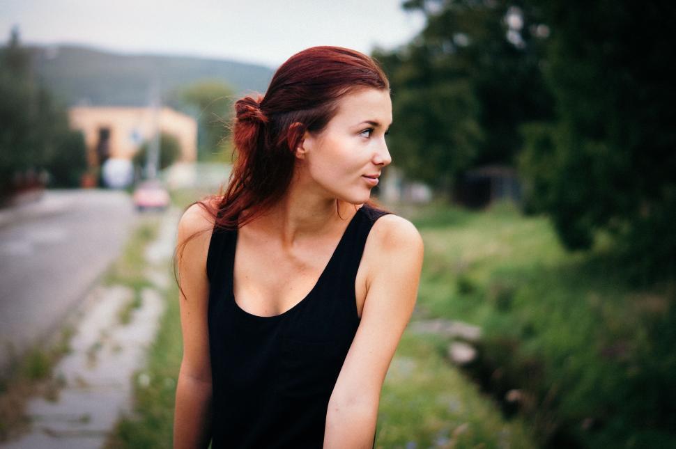 Free Image of Woman with red hair looking sideways outdoors in summer. 