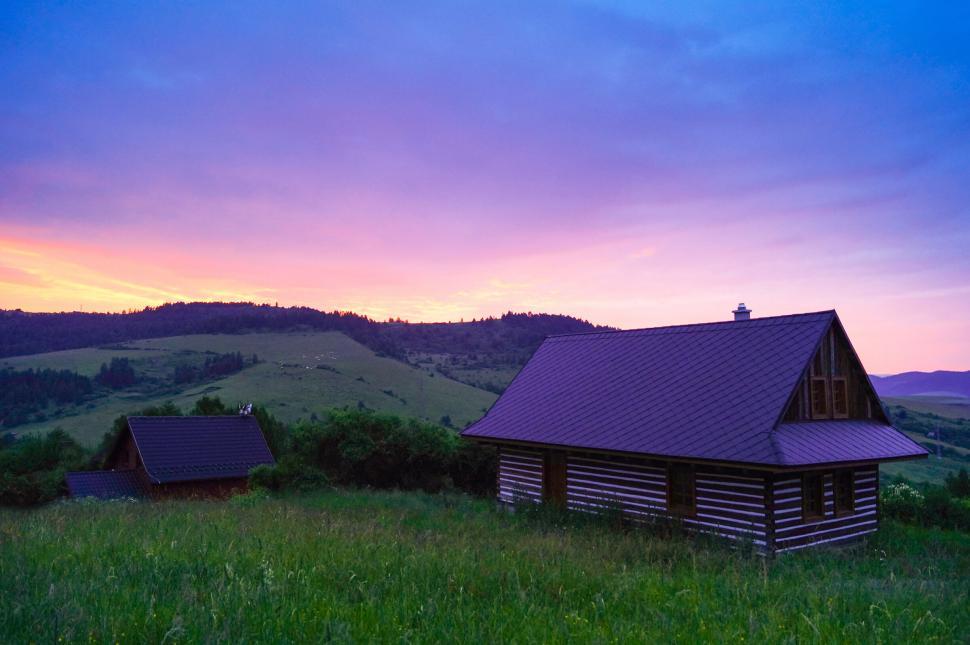 Free Image of Rural cottages amidst green fields during a vibrant sunset 