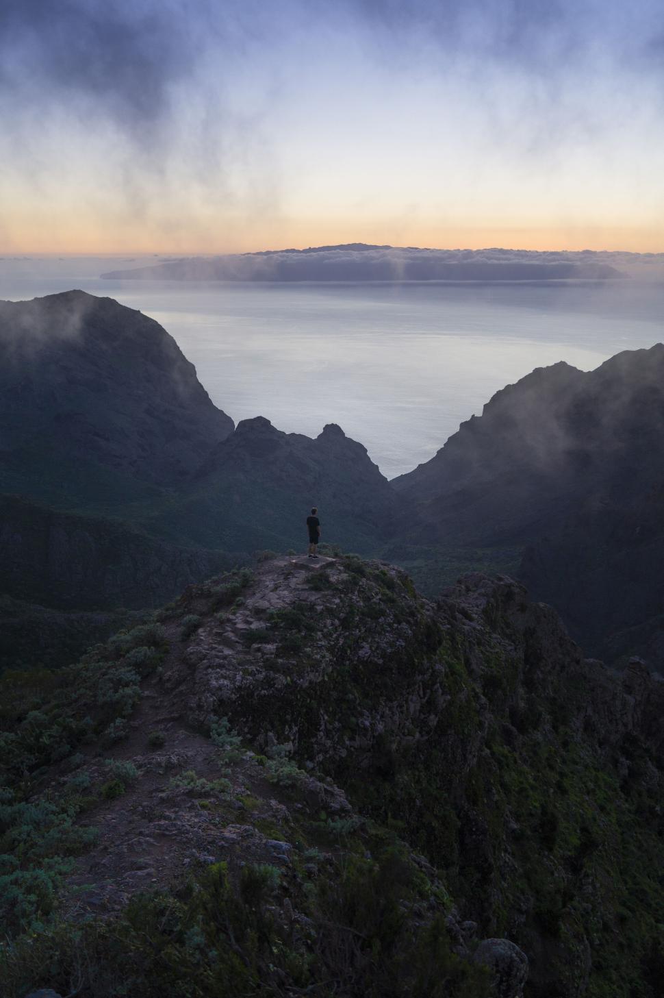 Free Image of Person standing on mountain peak at sunset with view. 