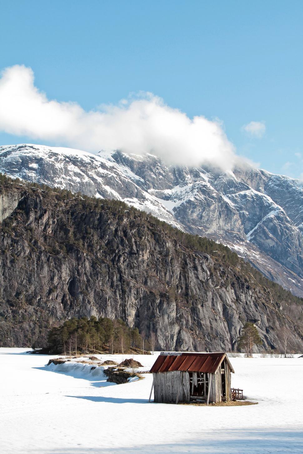 Free Image of Cabin in snowy landscape with majestic mountains behind. 