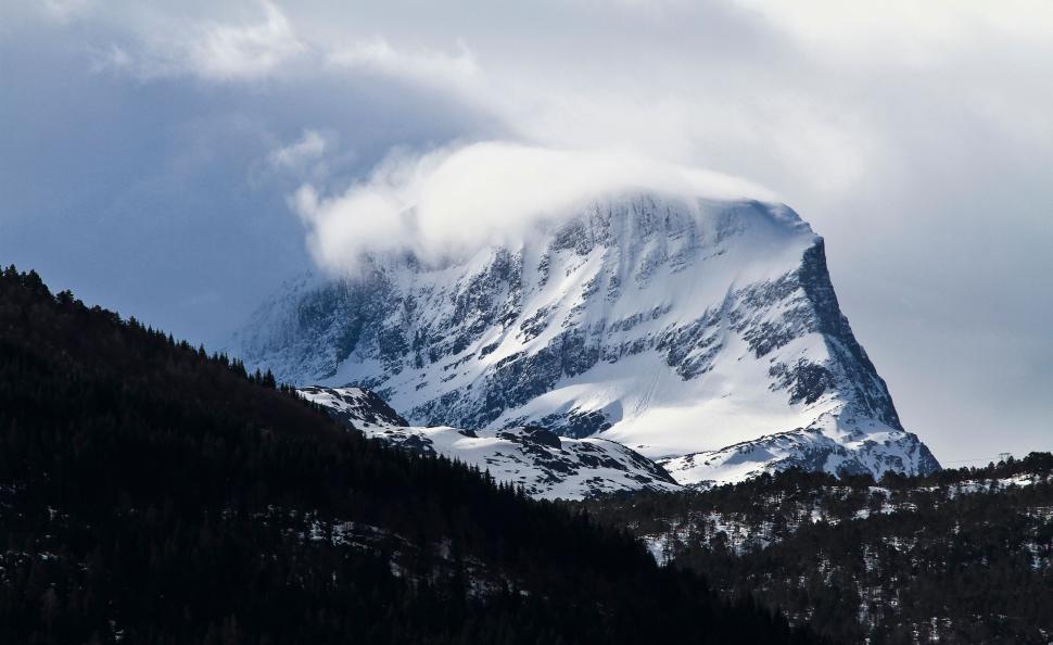 Free Image of Snow-covered mountain peak partially shrouded in clouds 