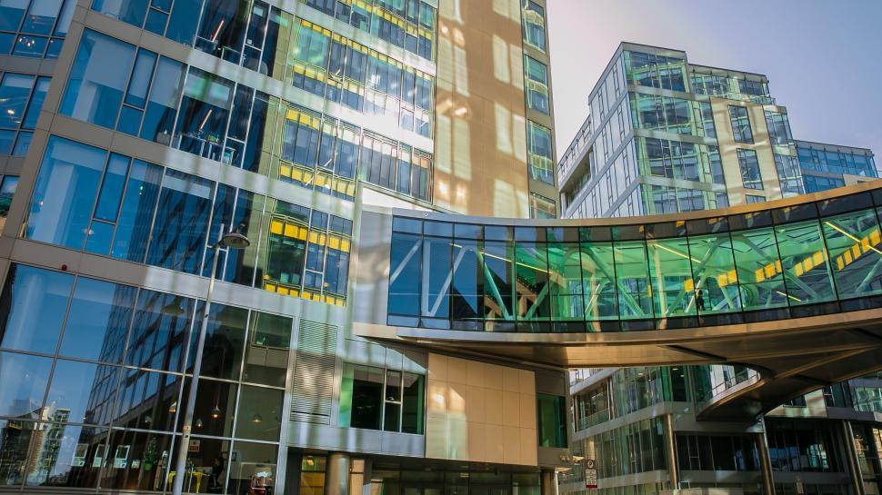 Free Image of Modern glass office building with connecting bridge in sun. 