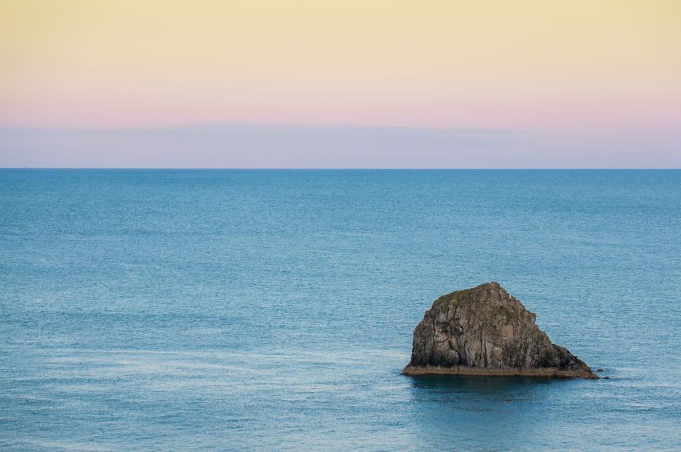 Free Image of Lone rock island in calm, blue ocean at sunrise 