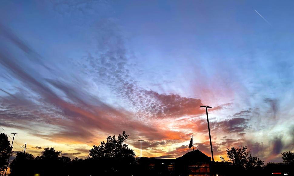 Free Image of Colorful sunset sky with light clouds and a flagpole 