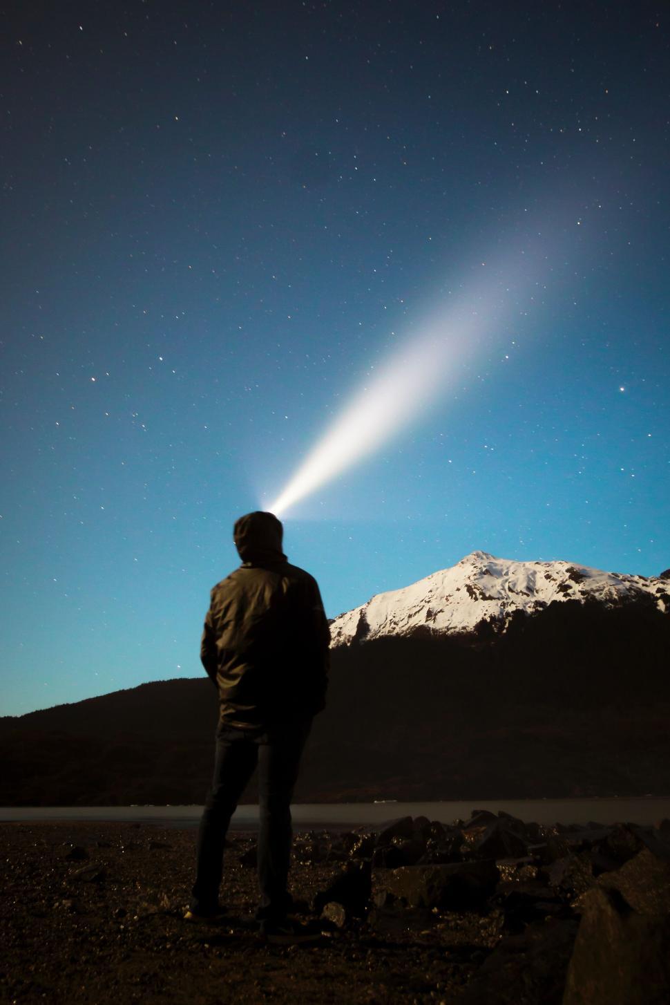 Free Image of A silhouette of a man with a headlamp under the night sky. 