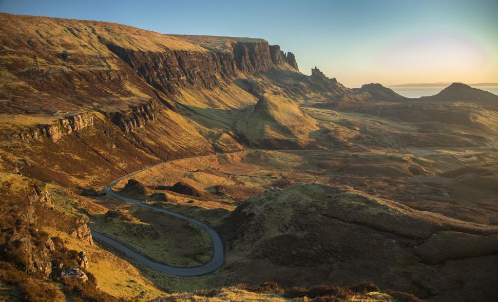 Free Image of Sunlit winding road through scenic mountain landscape 