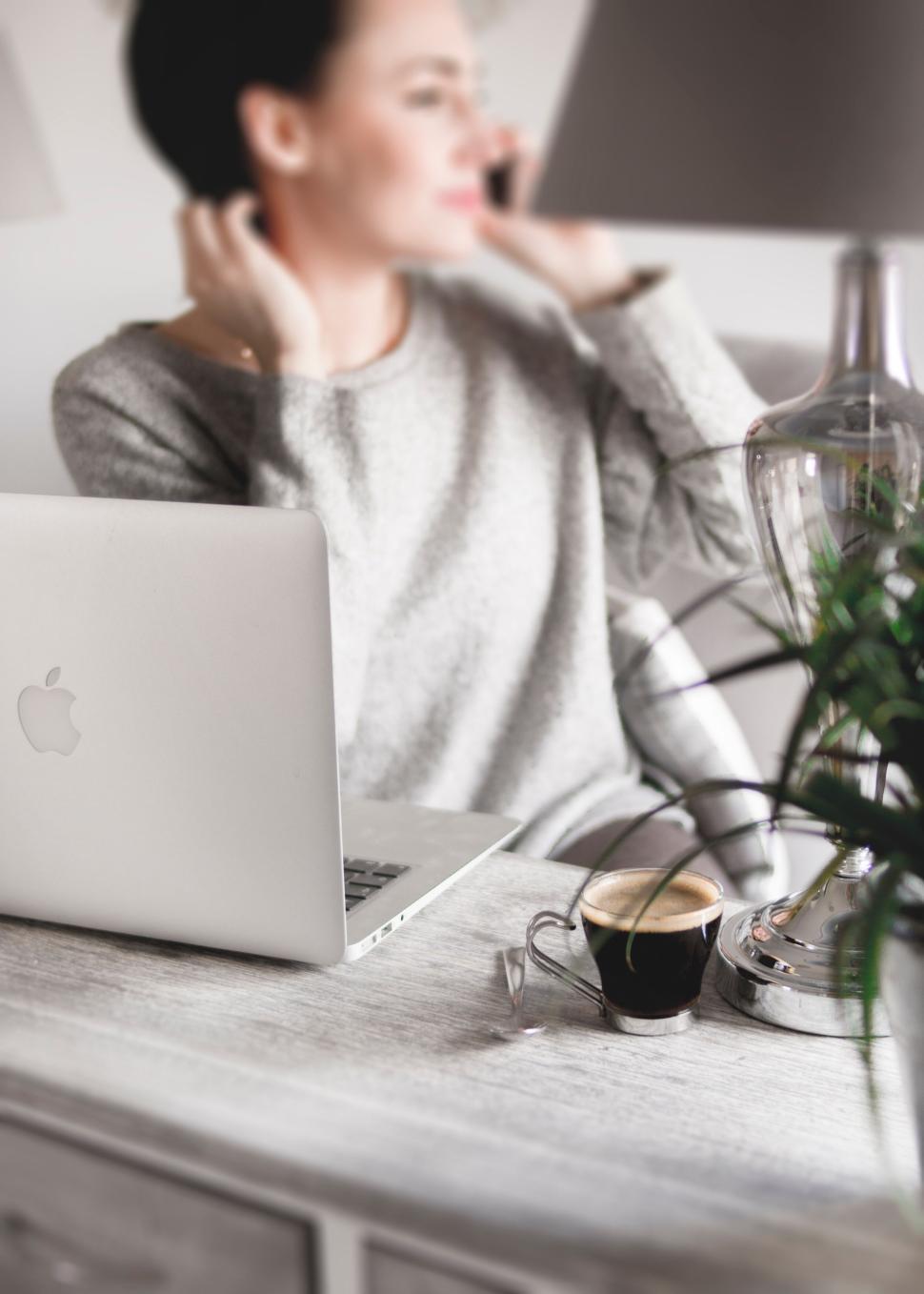 Free Image of Person working at a cozy desk with a MacBook laptop. 