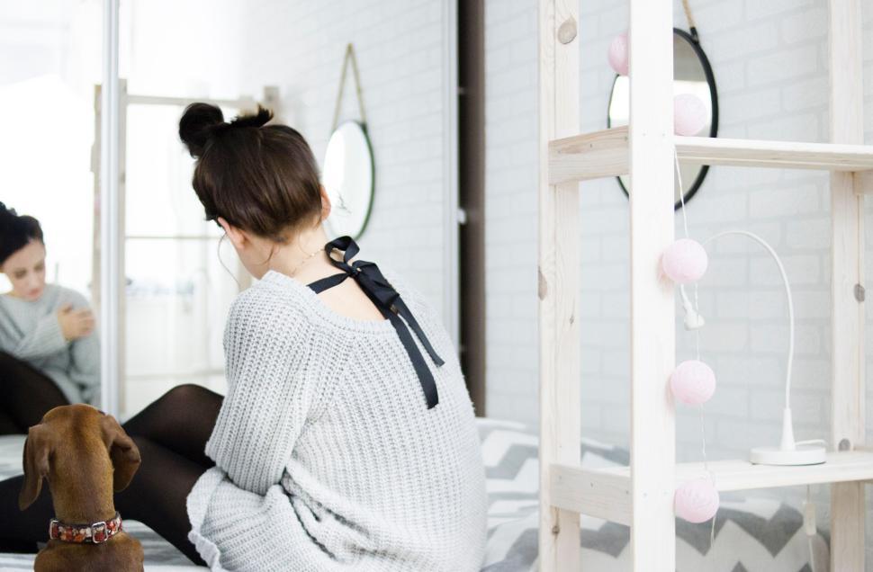 Free Image of Woman sitting with dog on bed, reflected in mirror 