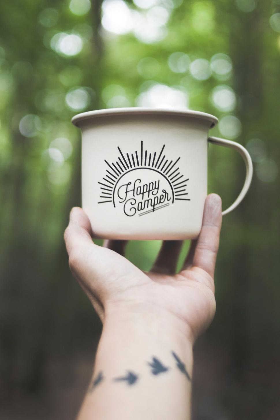 Free Image of Hand holding a white mug with Happy Camper text design 