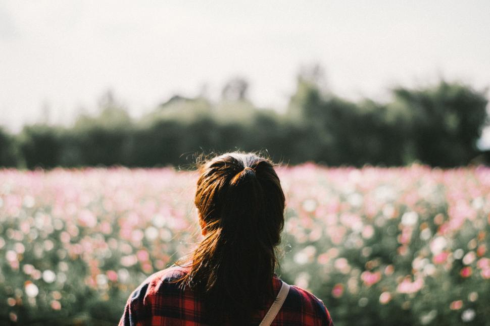 Free Image of Woman stands in a field of flowers looking forward. 
