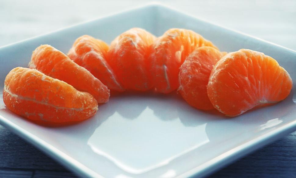 Free Image of Fresh orange slices arranged symmetrically on white plate. 
