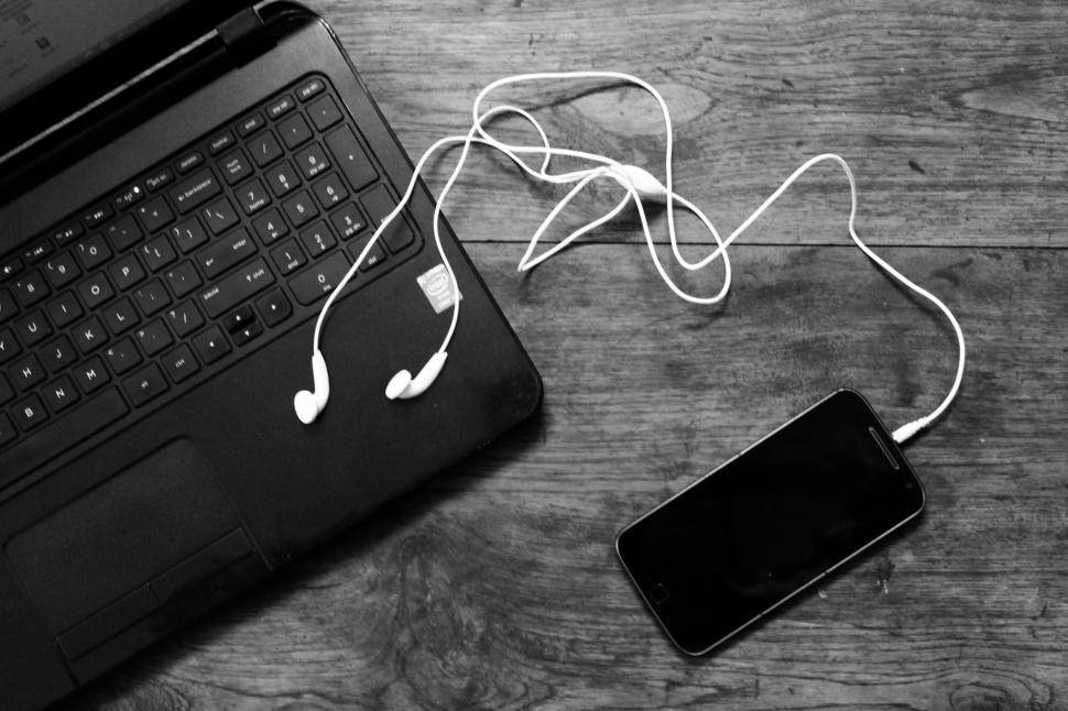 Free Image of Laptop and smartphone connected with white earphones. 
