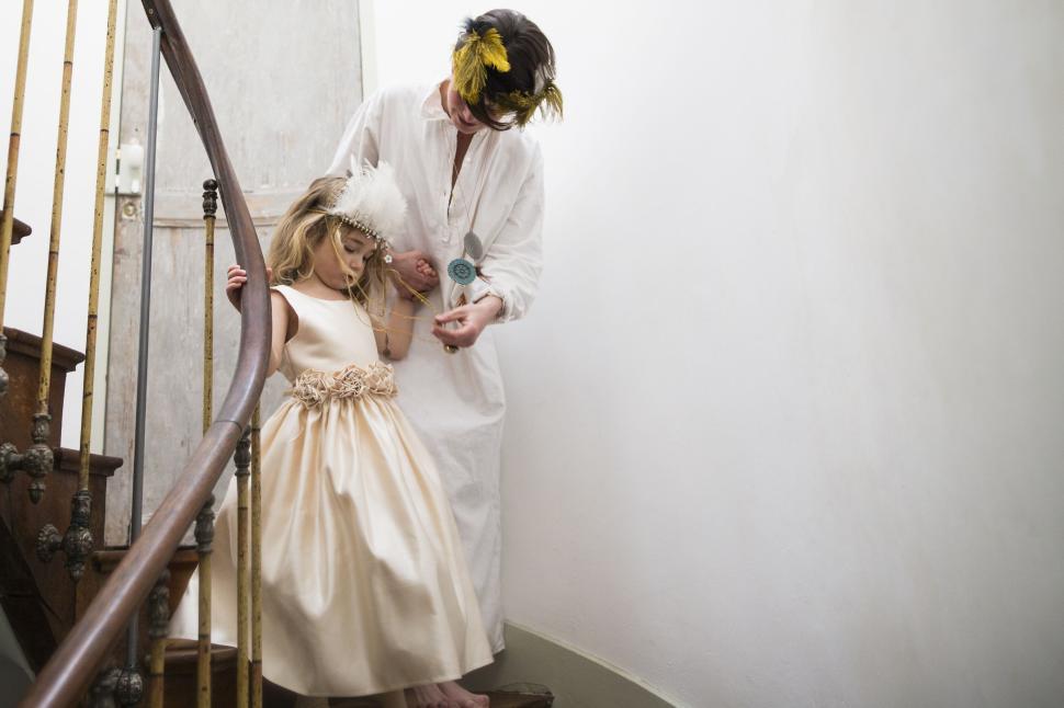 Free Image of Person in a long dress helping a child on wooden stairs 