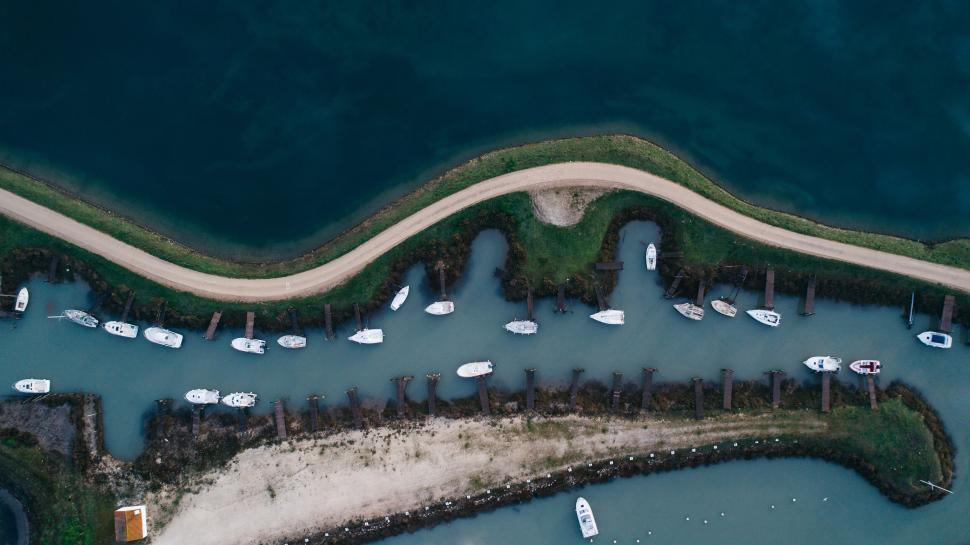 Free Image of Aerial view of boats docked in a curving waterway. 