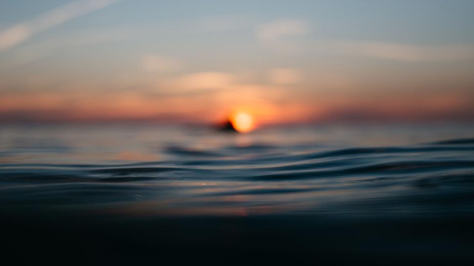 Free Image of Ocean water with distant blurred sunset on horizon 