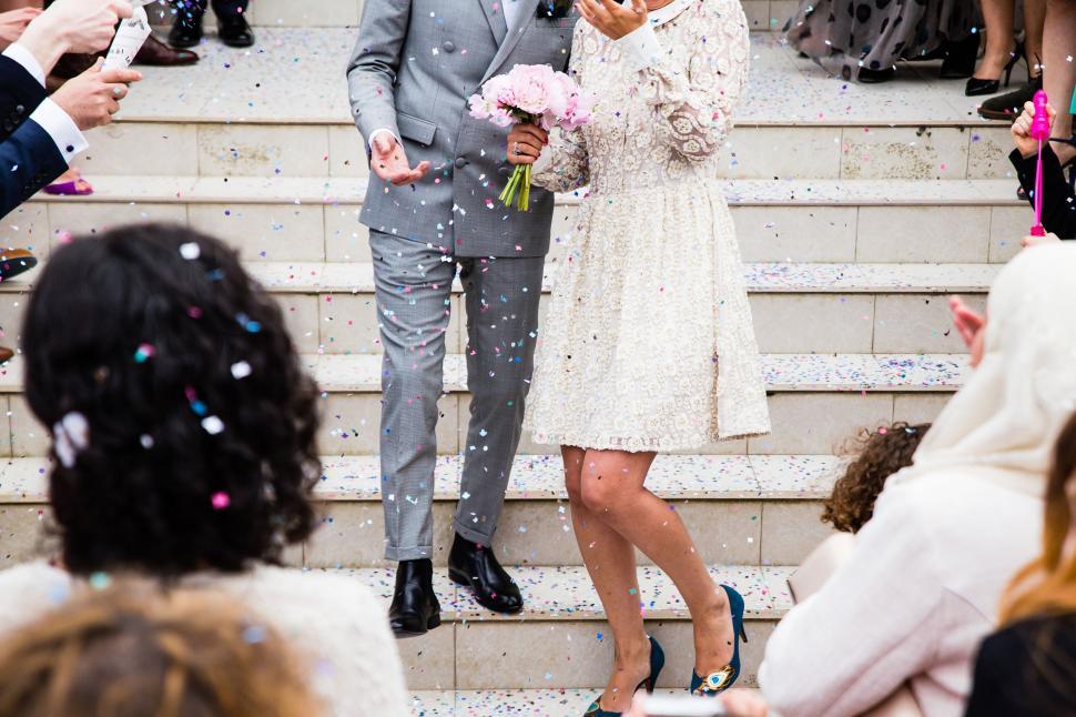 Free Image of Newlyweds embrace, surrounded by confetti on stairs 