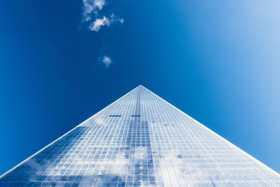 Free Image of Perspective shot of a tall glass skyscraper with clouds. 
