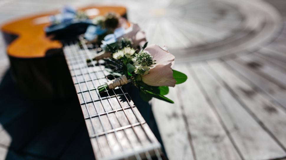 Free Image of Wedding bouquet placed on an acoustic guitar neck. 