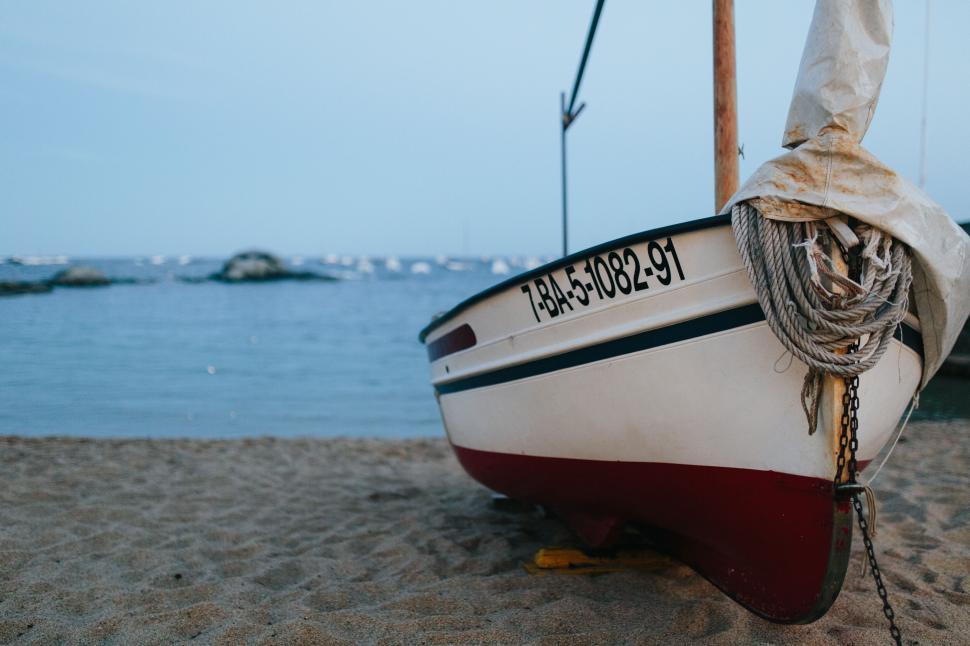 Free Image of Rowboat anchored on sandy beach with calm sea view. 