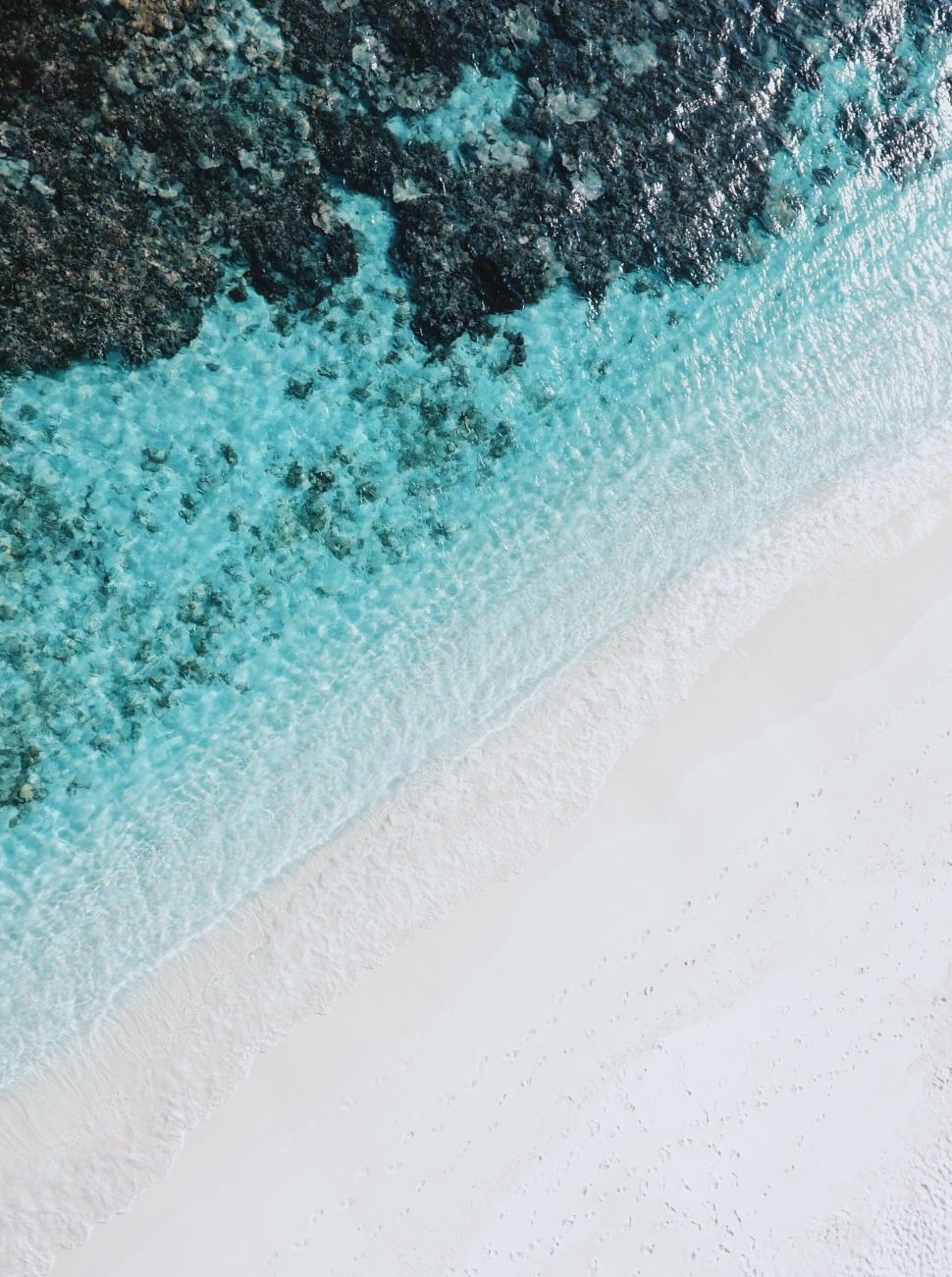 Free Image of Aerial image of shore with turquoise water and rock formations. 