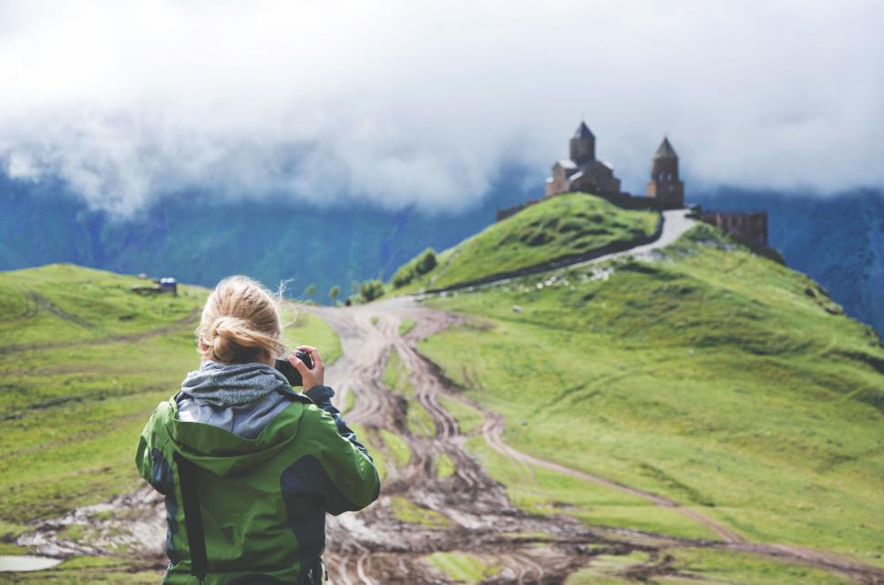Free Image of Traveler capturing remote church on lush green hilltop 