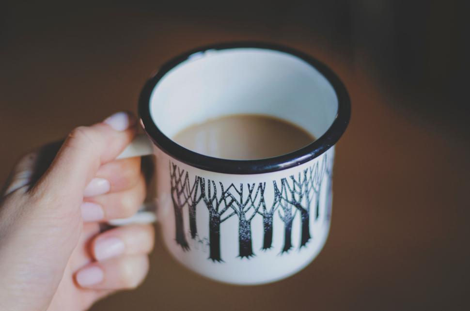 Free Image of Hand holding coffee mug with forest design and beverage 