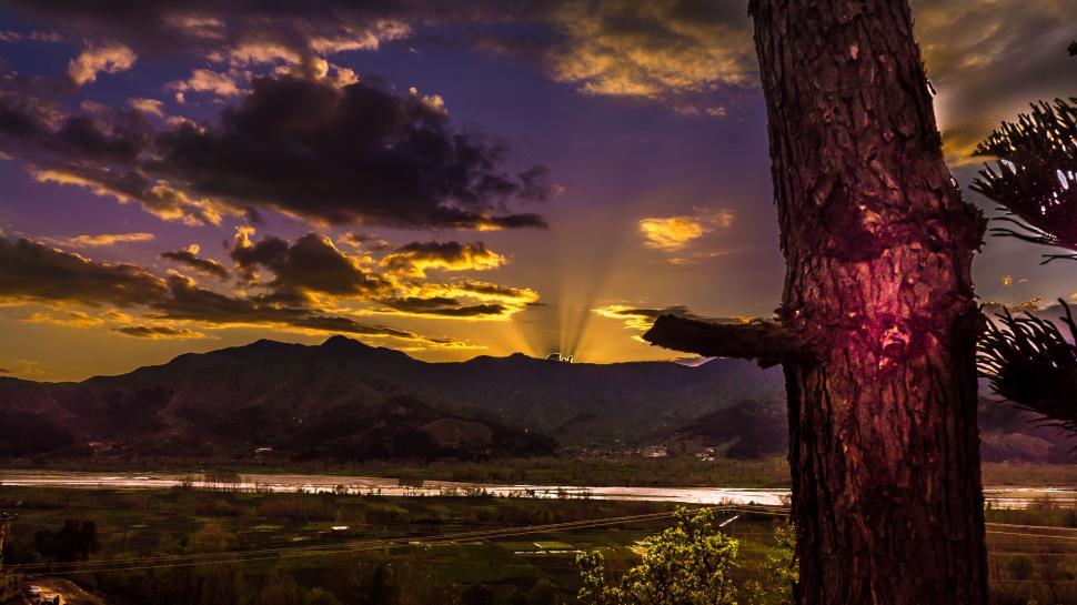 Free Image of Sunset with rays of sunlight over distant mountain range 