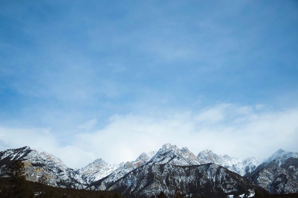 Free Image of Snow-covered mountains under a bright, clear blue sky 