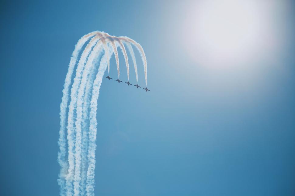 Free Image of Six jets creating vapor trails turn in a blue sky. 