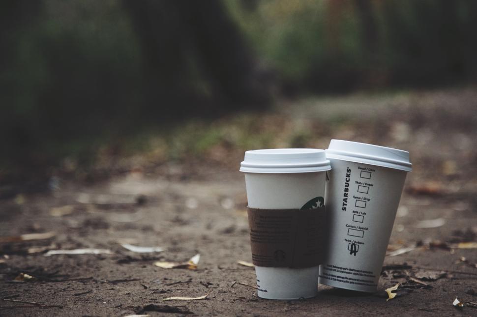 Free Image of Two takeaway coffee cups on ground with blurred background. 