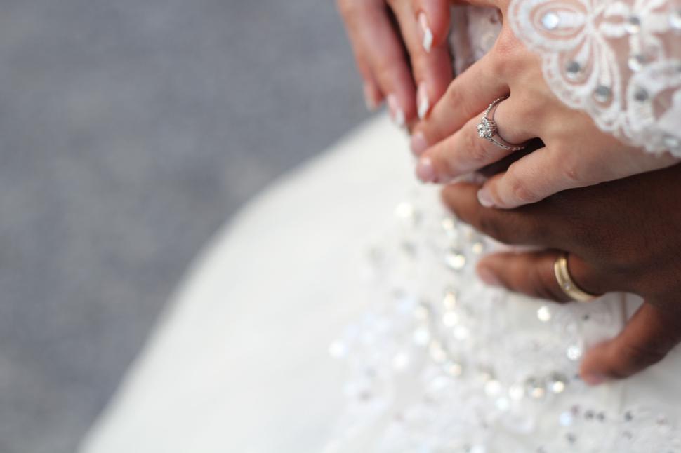 Free Image of Romantic couple holding hands in elegant wedding attire. 