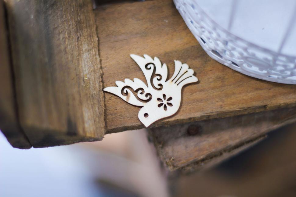 Free Image of Wooden bird ornament lying on a rustic wooden surface 