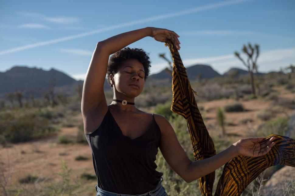 Free Image of Woman with scarf dancing freely in a desert setting 