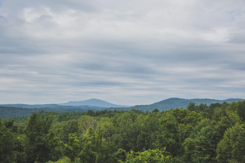 Free Image of Sweeping view of forested hills under cloudy sky 
