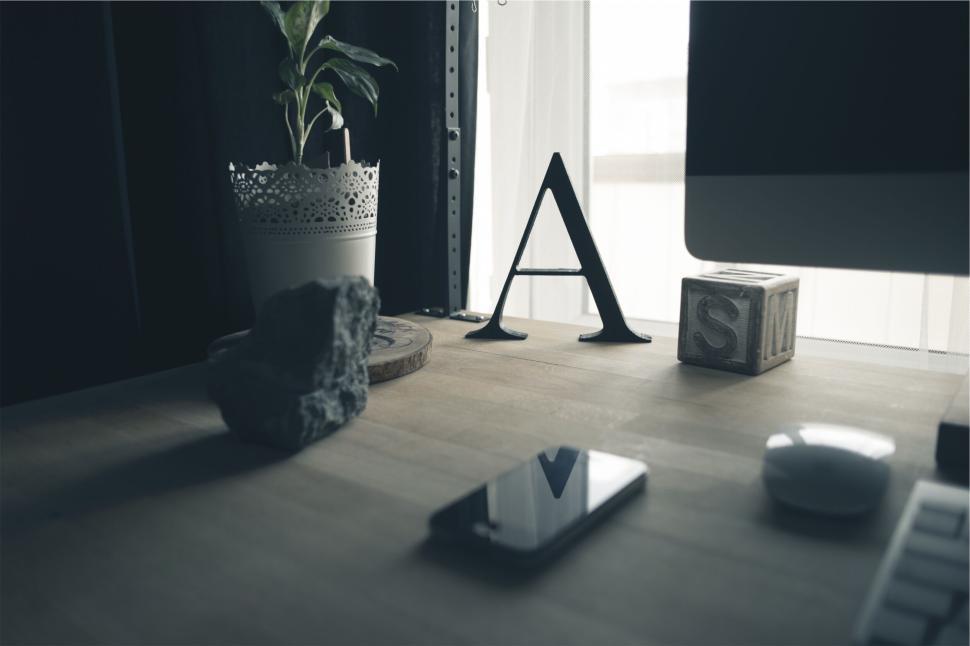 Free Image of Minimalistic workspace with letter A, plant, and phone 