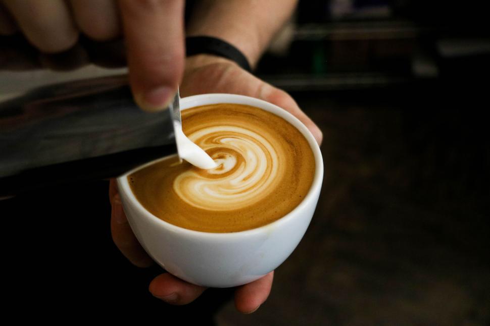 Free Image of Barista pouring milk into coffee creating beautiful latte art 