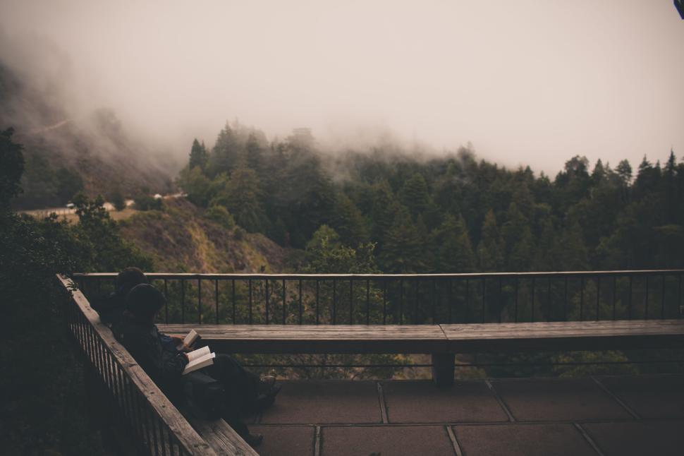 Free Image of Two people reading books on mountain top balcony 
