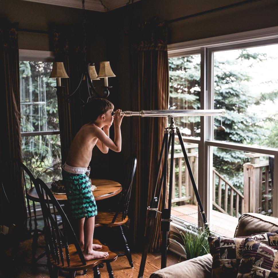 Free Image of Curious child looking through a telescope indoors. 