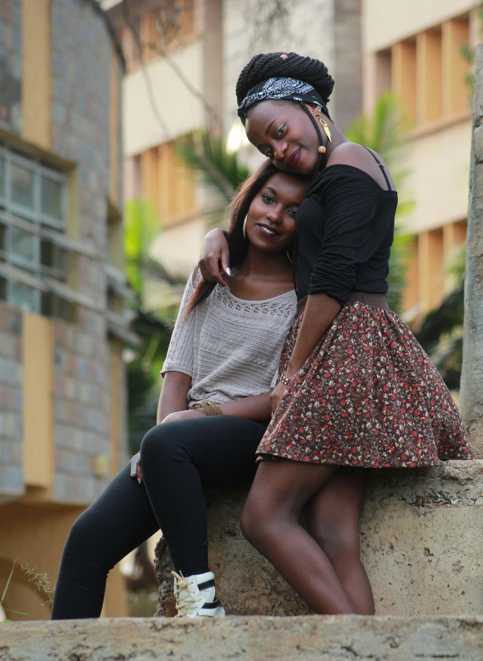 Free Image of Two women posing together, one standing one seated. 