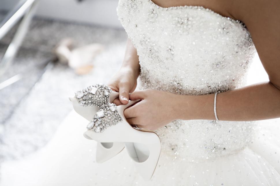 Free Image of Bride holding decorated shoes in her white wedding dress 