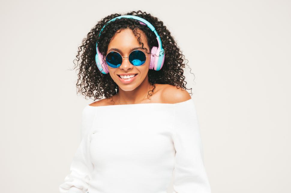 Free Image of Stylish woman in white top and headphones wearing sunglasses. 