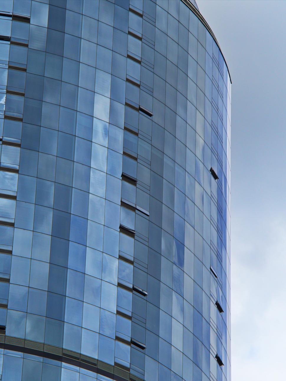 Free Image of Curved modern glass building with cloud reflections 