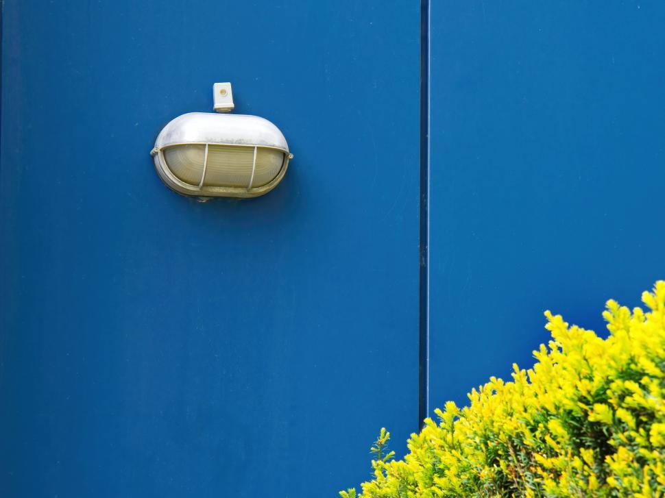 Free Image of Bright blue wall with an industrial light fixture. 
