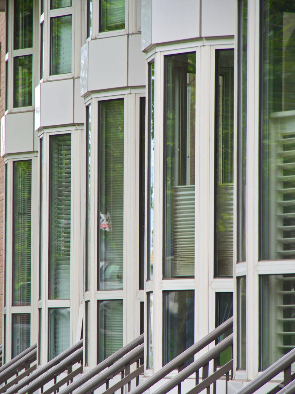 Free Image of Row of modern glass windowed balconies on a building. 