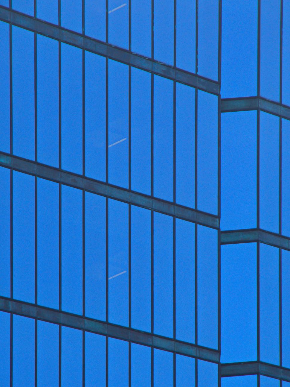 Free Image of Abstract view of glass building reflecting blue sky 
