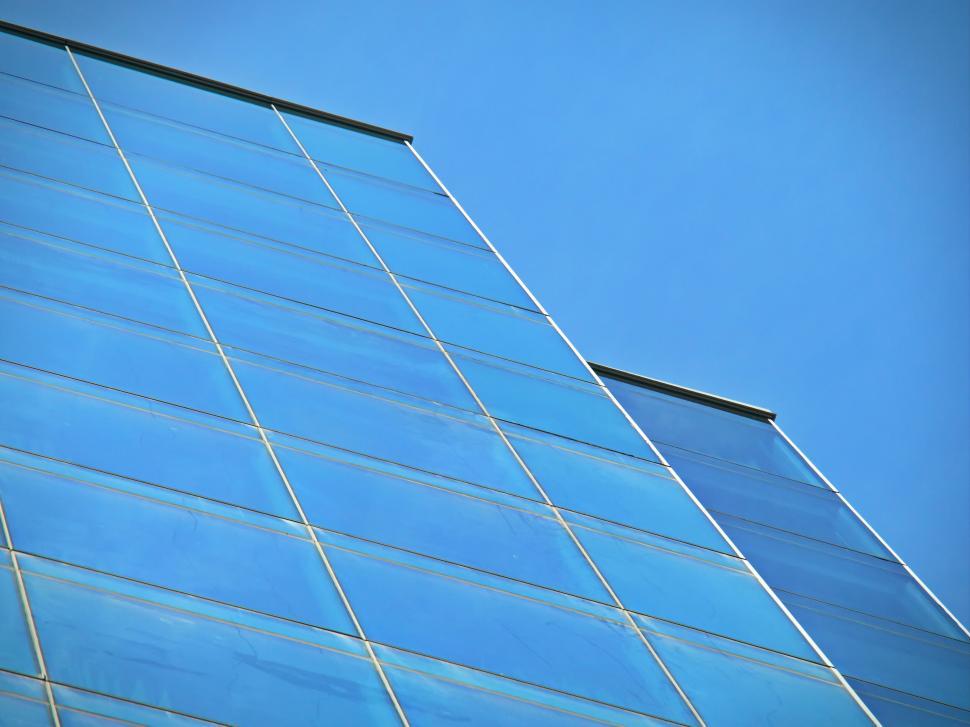 Free Image of Modern glass facade reflecting a clear blue sky 