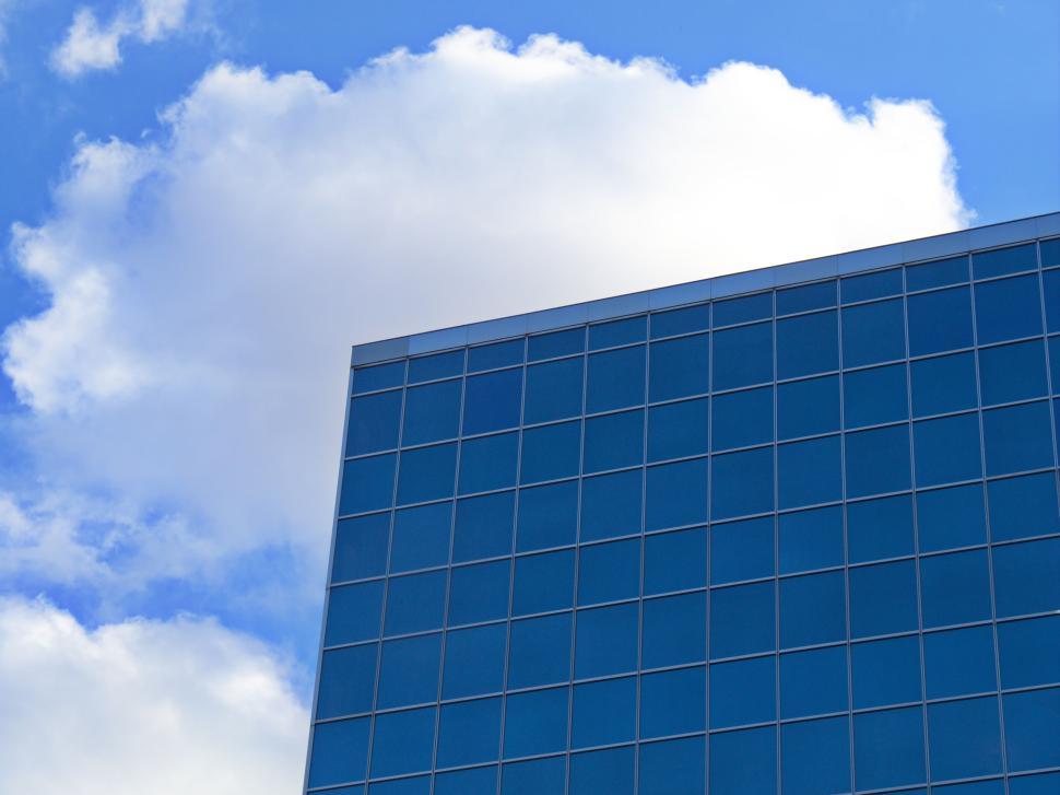 Free Image of Modern glass building with blue sky and clouds view 