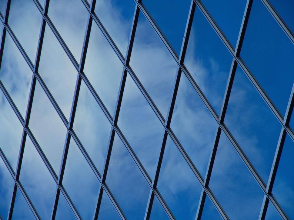 Free Image of Reflective glass building facade with blue sky view 