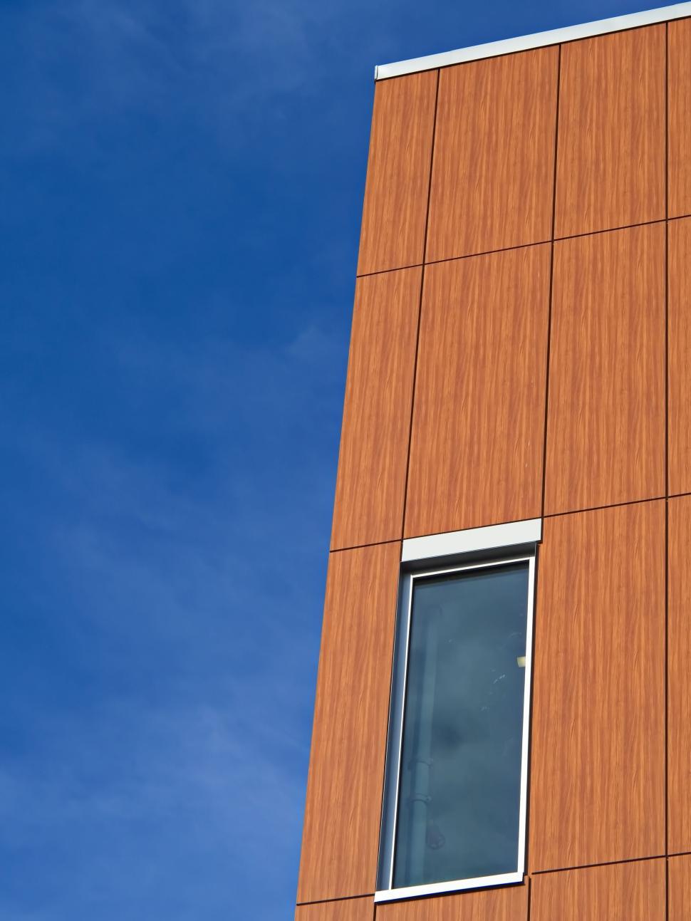 Free Image of Wood-textured building exterior with blue sky backdrop 