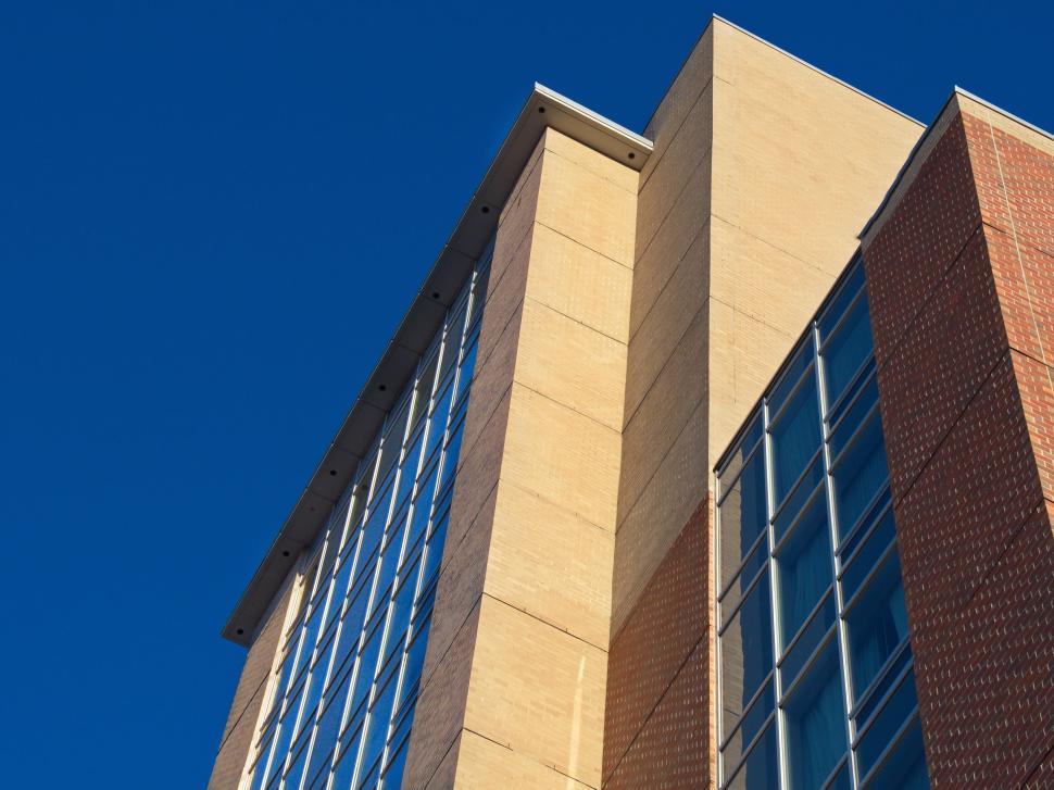 Free Image of Tall building with brick and glass facade against blue sky 